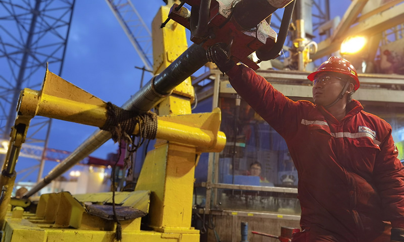 圖為套管作業人員用力扣合套管吊卡，確保篩管提升安全。