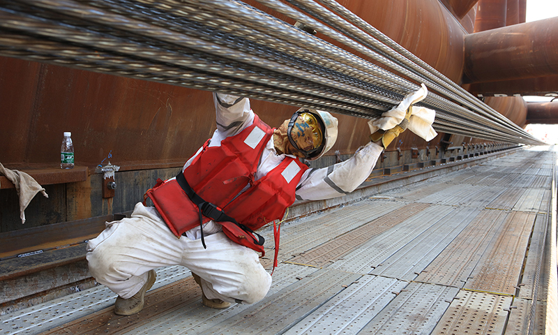 近日，經過約26小時的連續拖拉，在8組900噸拖拉千斤頂和2組400噸助推千斤頂的“同心協力”下，“海基一號”導管架順利登上位于珠海高欄港的運輸駁船指定位置。這標志著我國自主設計建造的亞洲第一深水導管架陸地建造全部完成。圖為裝船過程中施工人員不斷擦拭鋼絞線，為安全高效拖拉裝船提供保障。