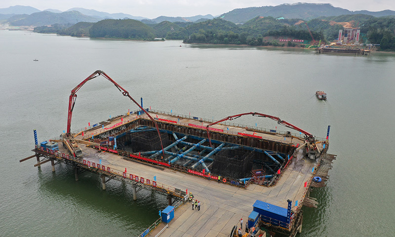 3月21日，在廣西上林至橫州高速公路建設施工現場，工人們加班加點完成控制性工程——西津郁江特大橋水中承臺的澆筑作業。圖為在廣西上林至橫州高速公路西津郁江特大橋建設現場，中鐵四局工人在進行水中承臺的澆筑施工作業（無人機照片）。（新華社記者 陸波岸 攝）