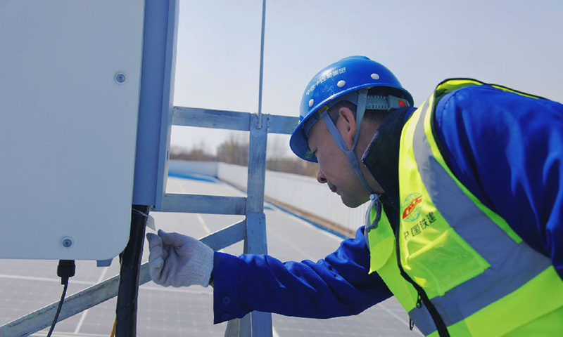 南水北調北京段房橋光伏發電項目位于太陽能資源豐富的北京市房山區，中鐵十四局電氣化公司施工建設者采取“自發自用，余電上網”方式進行設計，并采用全球領先的光伏組件，將太陽能通過光伏組件轉換為直流電，再通過逆變器將直流電轉換成交流電。圖為技術人員檢查現場設備。