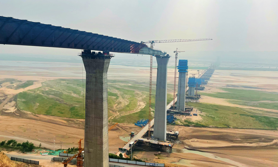 臨猗黃河大橋全長5427米，主橋采用等高度連續鋼箱組合梁，從山西、陜西兩側頂推平臺相向頂推施工，單跨最大長度為128米，共30跨。中鐵工業主要承接了該橋主橋陜西側共計約3.03萬噸鋼結構、檢修機構箱軌道、附屬結構的制造任務。圖為施工現場。