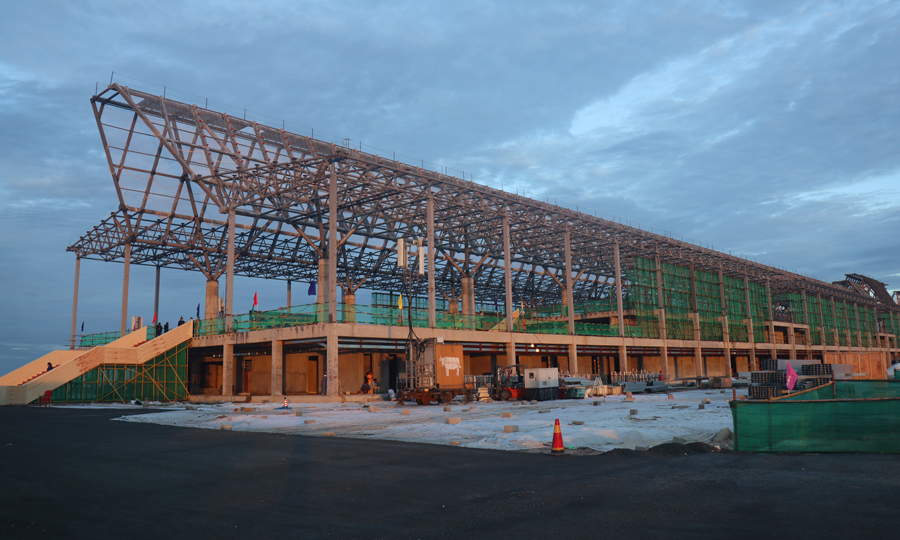 暹粒吳哥國際機場項目飛行區跑道長3600米、寬45米，是飛行區的主體工程。跑道混凝土工程自今年1月16日正式啟動以來，克服疫情、高溫、降雨、地材緊張、海運周期長等不利因素影響，積極引進滑模攤鋪機施工，顯著提升了道面混凝土的施工質量和效率，歷時125天，完成7萬立方米的混凝土澆筑，提前10天完成節點任務。圖為機場航站樓項目施工現場。