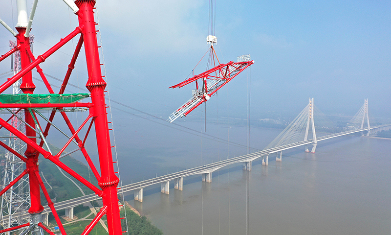 8月1日，經過建設者150余天的奮戰，白鶴灘至浙江±800千伏特高壓直流輸電工程安徽池州長江大跨越高345米的南岸跨越塔成功封頂。圖為當日，安徽送變電工程有限公司施工人員在池州長江大跨越南岸跨越塔封頂施工現場作業（無人機照片）。趙獻富 攝