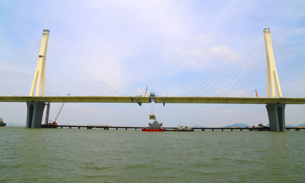 據悉，金海特大橋鋼結構由4個鋼主塔、8個大節段鋼梁、39塊標準鋼箱梁（含3個合龍塊）組成，鋼梁及鋼塔共計5.2萬噸。目前，大橋已全面進入橋面系統施工階段，計劃四季度進入鋪軌階段，明年達到通車條件。圖為金海特大橋合龍現場。