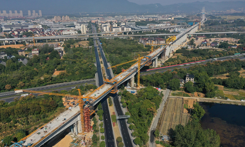 10月20日，由中鐵上海工程局承建、位于浙江杭州桐廬縣境內的杭溫鐵路二期工程跨杭黃鐵路特大橋長達390米的連續梁順利合龍，這是杭溫鐵路二期工程實現合龍的最大跨度連續梁。圖為10月20日拍攝的杭溫鐵路二期工程跨杭黃鐵路特大橋完成合龍的最大跨度連續梁（無人機照片），該連續梁同時上跨杭新景高速公路和桐廬縣鳳川大道。新華社記者 黃宗治 攝