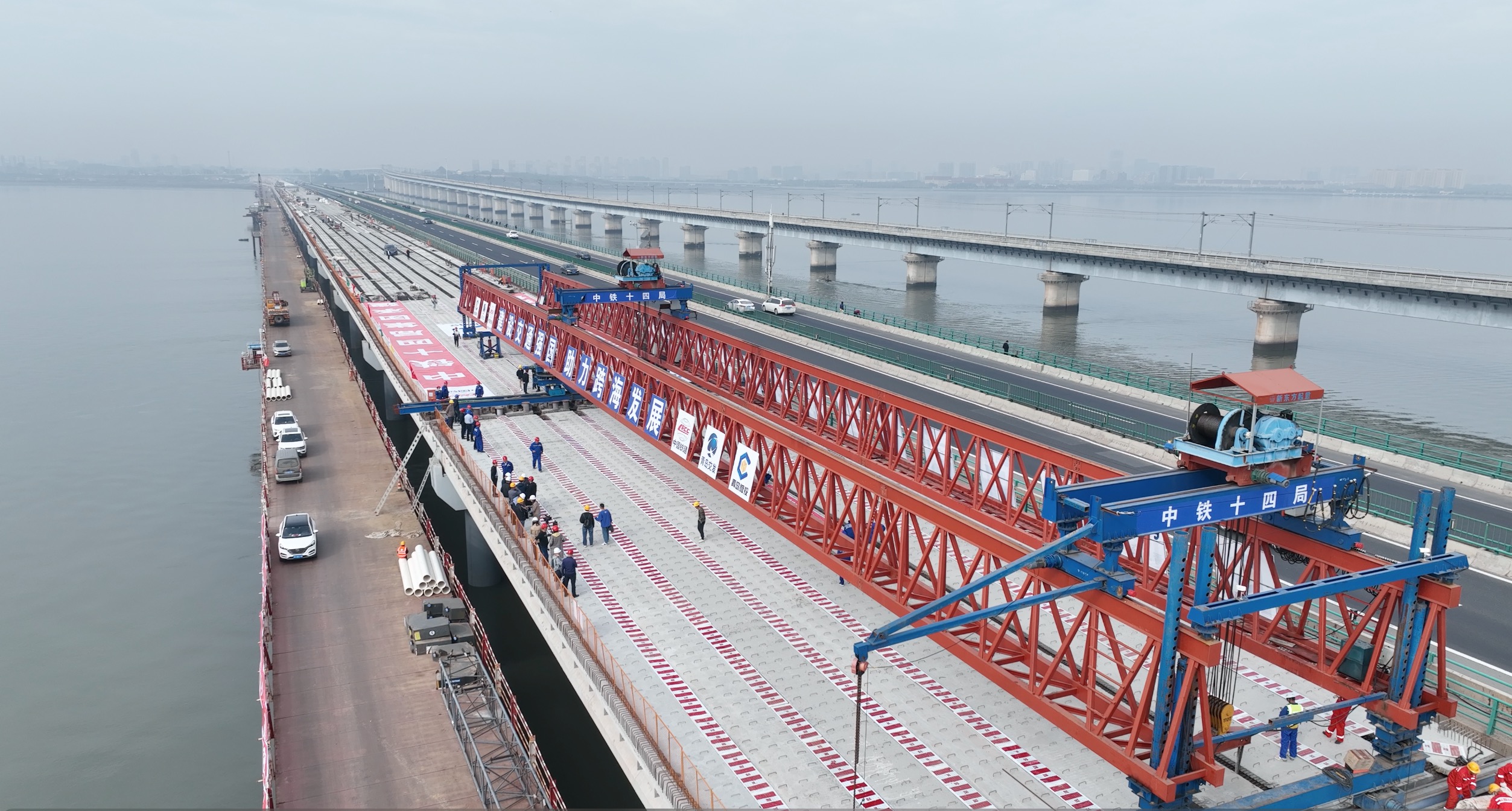 青蘭高速擴建工程女姑口特大橋全長3167.5米，橫跨膠州灣海域，常年受潮汐侵襲，地處海面開闊地帶，全年大風天氣，歷年最大風力可達11級。項目部采用雙梁場3條生產線同時施工，利用裝配式施工的優勢，大大壓縮了海上作業時間，最終實現8個月順利合龍。圖為項目施工現場。