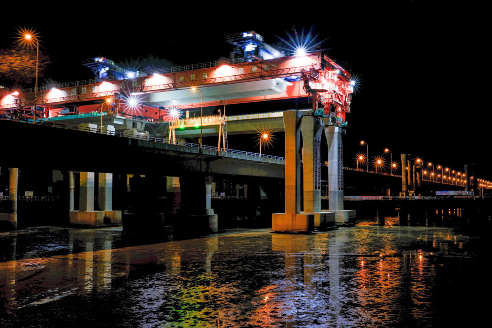 項目團隊圍繞海上50米大跨徑、1800噸超大噸位整孔預制箱梁運輸兩個方面開展科研攻關，研制了我國自主研發、目前世界上最大的公路架橋機“越海號”開展“梁上運架”施工，成功攻克箱梁單體重量大、超高橋面漸變橫坡、高低墩及1800米超小曲線半徑等技術難題，確保了箱梁架設和金塘大橋運營安全，創下了國內采用“梁上運架”技術單體最重的整孔預制箱梁施工紀錄。圖為跨金塘大橋架梁施工現場。