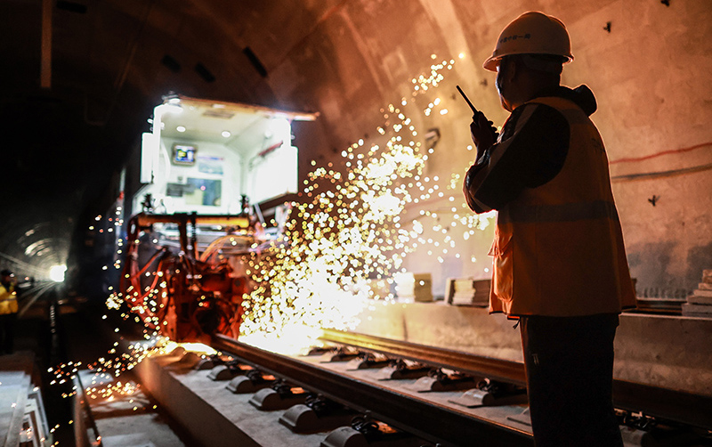 截至11月11日，貴南高鐵貴州段正線鋪軌已完成近200公里，超過388公里正線鋪軌任務的一半，為全線鋪軌完成和按期開通運營奠定了堅實基礎。貴南高鐵連接貴州貴陽和廣西南寧，是我國“八縱八橫”高速鐵路網包海通道的組成部分，設計時速350公里。圖為中鐵一局員工在貴南高鐵貴州獨山段一條隧道內指揮焊軌機施工。新華社記者 劉續 攝