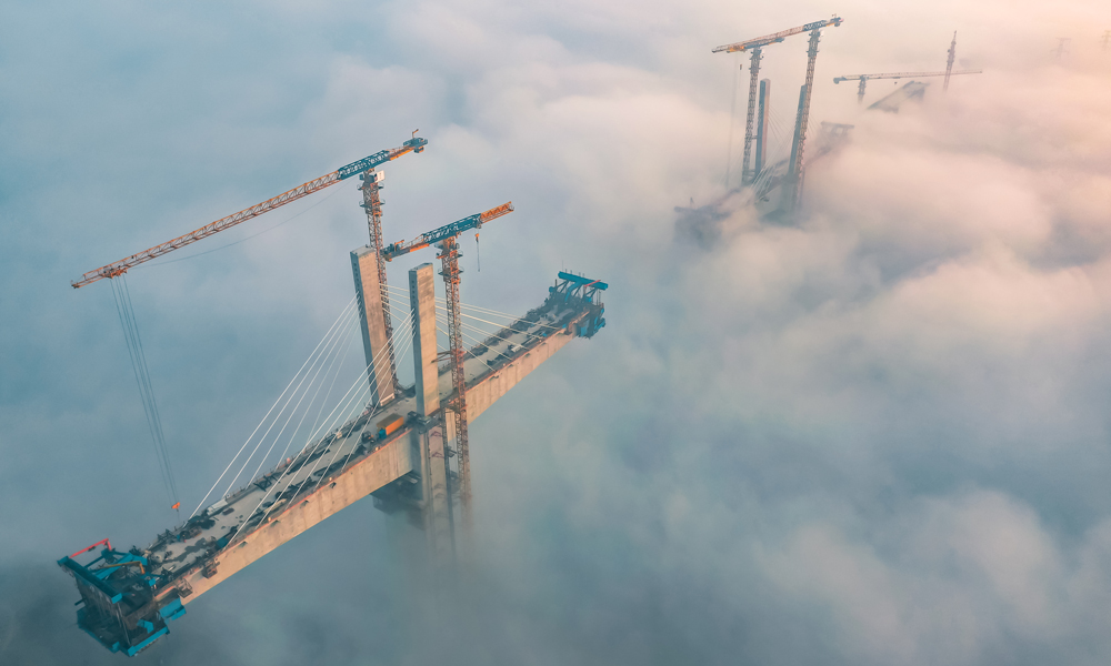 11月15日，大霧籠罩，在渝昆高鐵（川渝段）重點控制性工程——瀘州沱江特大橋項目建設現場，中國中鐵旗下中鐵四局建設者在100余米的高空進行斜拉索掛索及懸臂節段掛籃懸澆作業。