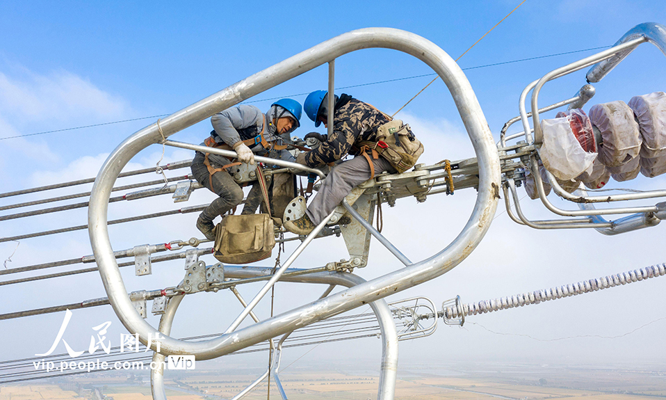 2022年11月23日，在1000千伏特高壓盱眙至泰州線路升高改造工程現場，江蘇省送變電有限公司施工人員正在百米高空架設導線。本次升高改造共組立新鐵塔4基，拆除舊鐵塔3基，將輸電線路對地安全距離由原來的19米提高至30米，保障阜興泰高速公路建成后車輛通行安全。同時，將進一步提高電網可靠性，確保迎峰度冬期間電網安全供電。史俊 攝
