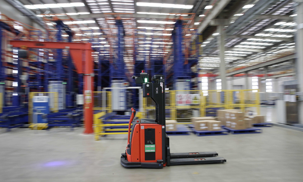 數字化智造管控系統（DIMS）是指揮自動化生產線的大腦。在項目啟動期，從DIMS發往生產執行系統的工單總是發送失敗，生產一度陷入停滯。經過一次次不懈努力，項目組終于完成系統迭代，為后續系統開發提供了寶貴經驗。圖為在基地智能倉儲中心，無人駕駛叉車正在作業。