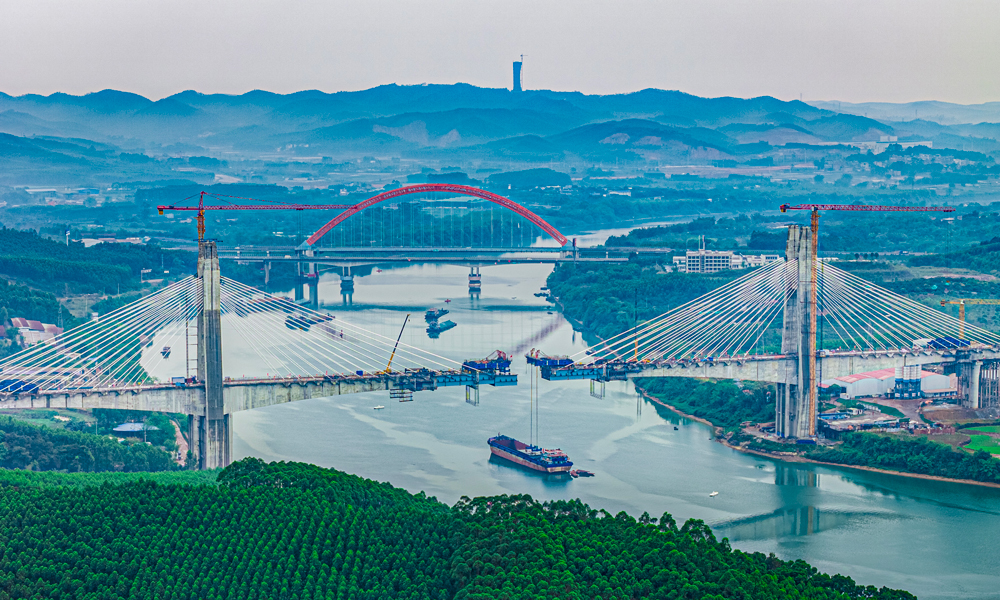 六律邕江特大橋跨越邕江東西兩岸，采用墩塔固結、墩梁豎向支撐的半漂浮結構體系。主橋全長622米，橋梁主跨長320米。開工建設以來，建設團隊持續優化施工方案、強化現場管控，嚴格執行各項施工規范及操作規程，克服了地質熔巖發育、超深流沙層、超大溶洞、高塔施工難度大、懸臂澆筑長等難題，圓滿完成大橋建設任務。