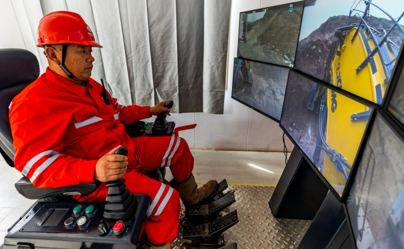 在準能集團黑岱溝露天煤礦智能礦山建設現場指揮中心，700噸級液壓正鏟司機正在通過遠程操控方式配合300噸級礦用無人駕駛卡車進行裝車作業。該系統模擬駕駛艙真實駕駛環境，采集駕駛室內真實聲場信息，輔以低延時、高帶寬的5G通信技術，對信號、圖像、數據和指令進行傳輸，實現在辦公樓內實時、精確遠程控制液壓正鏟作業。李瑞榮 攝