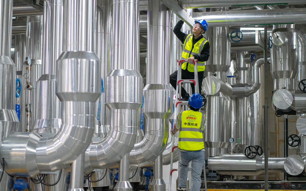 通過博鰲近零碳示范區運行管理中心，可以實現整個零碳示范區碳監測、碳核算及智慧化運維。中心搭載了智慧能源管控平臺，該平臺運用“CIM+BIM”建設3D數字孿生東嶼島模型，接入樓宇管控、燈光照明、環境監測等系統，可視化監測管控，定期反饋設備運行狀態，根據建筑空間人數及室外光照強度，動態調節空調及燈光。圖為中鐵建設運維工程師檢查制冷機房設備運行狀態。