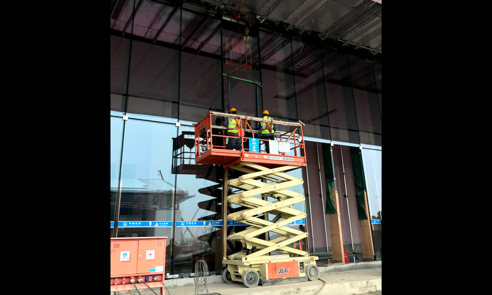 施工團隊工作人員嚴格按照玻璃編號安裝，從材料起吊到完全安裝好一塊玻璃幕墻需要近40分鐘。圖為4月13日，中建裝飾建筑工人正在吊裝FS2底層坐式全玻幕墻。（國務院國資委網站 李子紅 攝）