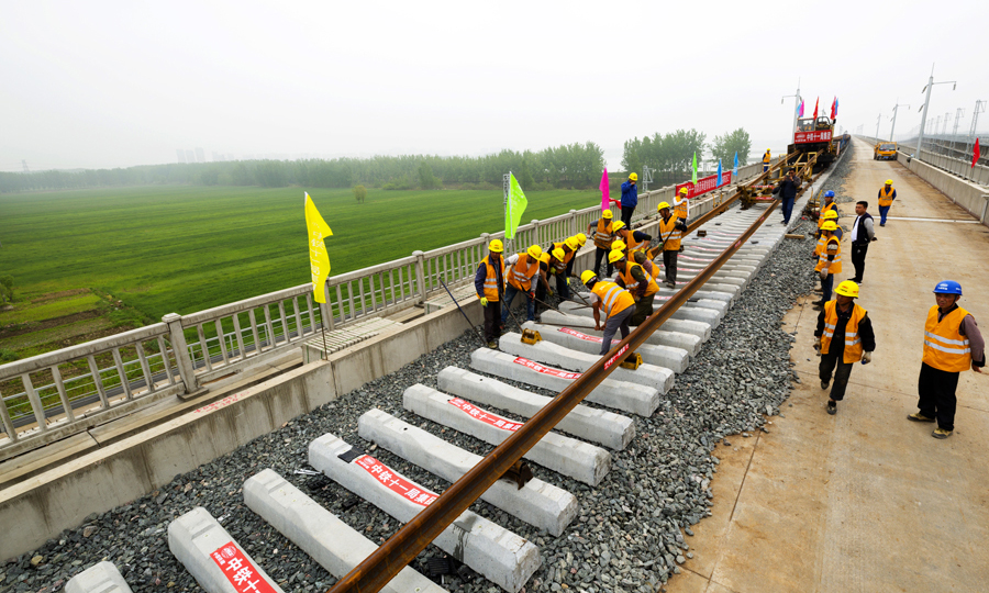 4月23日11時39分，在江蘇省徐州市賈汪區大湖村后馬莊特大橋，WZ500鋪軌機組將最后一對500米長鋼軌鋪設完成并與徐州東站徐淮場202號道岔順利接軌，標志著由中國鐵建所屬中鐵十一局全線鋪軌施工的徐宿淮鹽鐵路正線長軌道貫通，為年底具備通車運營條件奠定了堅實基礎。圖為鋪軌作業現場。