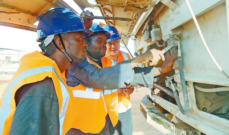 在安哥拉二期大市政項目建設中，為確保工程如期履約，中國鐵建所屬中鐵十四局通過開展技術革新、提高機械設備能效、大量聘用當地工人等措施，既加快了工程進度，又節約了施工成本，為解決當地就業、加快經濟發展作出了積極貢獻，贏得了當地居民和政府的好評。圖為當地時間10月28日，安籍員工在中方技術人員指導下檢修施工車輛。（周存泉 攝）