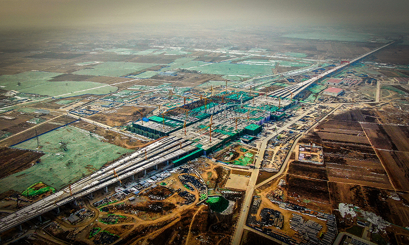 由中國鐵建所屬中鐵十二局參建的京雄城際鐵路雄安站房項目是雄安新區第一個開工的重大交通建設項目。目前該項目正在進行上部鋼結構作業和下部架體拆除，即將轉入站房內部裝飾、機電安裝作業，站房預計于今年年底建成。圖為雄安站施工現場。（任雙歡 攝）