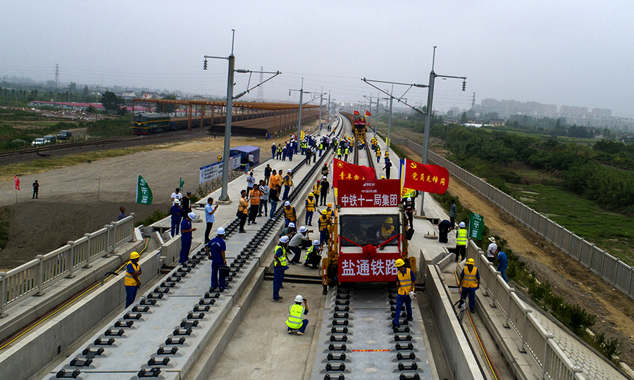鹽通高鐵全線采用500米長鋼軌鋪設，按一次性鋪設、跨區間無縫線路設計，軌道鋪設完成后，采用國內先進的移動閃光焊技術，將鋼軌焊接、鎖定成一根超長無縫線路，高鐵軌道的精度堪比發絲，實現“如絲般順滑”，有效地防止鋼軌的熱脹冷縮，減少列車與鋼軌接頭的震動，保證高速列車的行駛更加安全，旅客乘坐更加舒適。圖為鹽通高鐵全線首鋪現場。（劉連強 攝）