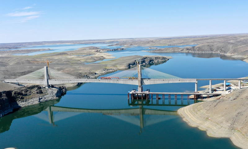 7月2日，隨著最后一組25米軌排推進落地，新疆阿富準鐵路（阿勒泰-富蘊-準東）的阿勒泰至富蘊段順利鋪通，標志著阿富準鐵路已全線貫通，北疆鐵路環線也正式形成。圖為中鐵一局的施工人員在喀拉塑克水庫1號大橋上進行鋪軌作業。（新華社記者 丁磊 攝）