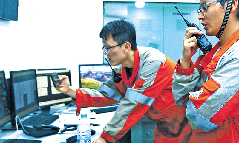 初秋的遼東灣，海面風平浪靜。一艘歸航的拖輪犁開一條長長的水線，船影消逝了，水線卻久久留存。平臺長秦斌無暇遠眺，聽到對講機中“秦臺秦臺，請給中控回電”的呼叫聲，趕忙從飛行甲板快步趕往中控室。圖為平臺長和中控緊盯現場數據。