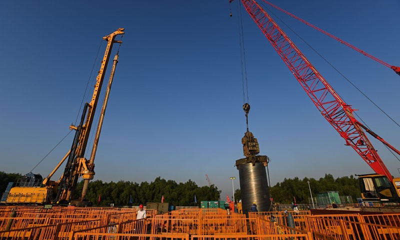 該項目與深中通道形成Y型路網，北連廣州南沙，南通珠海（澳門），西進中山（江門），東接深圳（香港），串聯起大灣區核心區域東西南北大通道，項目計劃2024年與深中通道同步建成。圖為10月26日，施工人員在位于廣州南沙區的南中高速洪奇門特大橋東塔平臺吊裝鋼護筒。（新華社記者 劉大偉 攝）