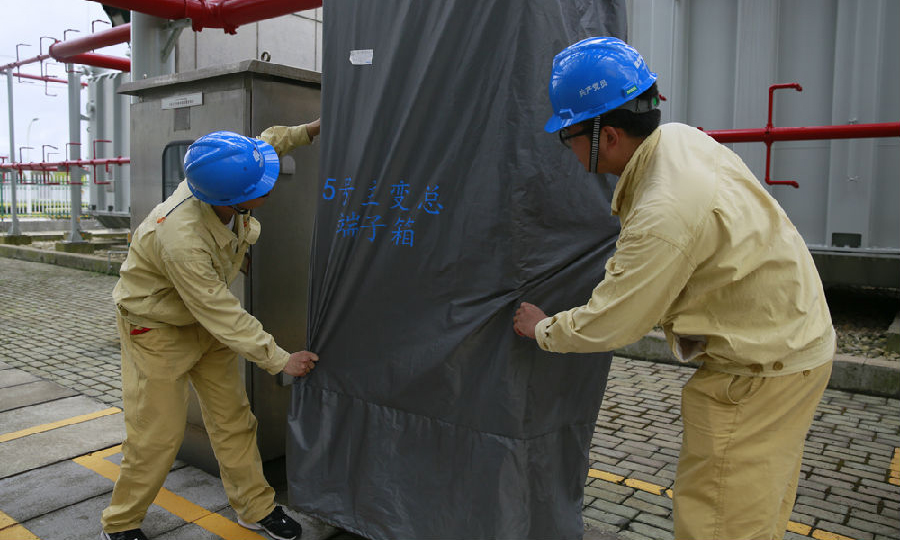 國華電力寧海電廠維護檢修部門充實防汛儲備物資的品種和數量，對經常性故障設備和室外設備進行精益化維護升級，確保設備在汛期穩定運行。圖為該廠團員青年對5號機主變區域控制室外電源箱加裝防雨布。